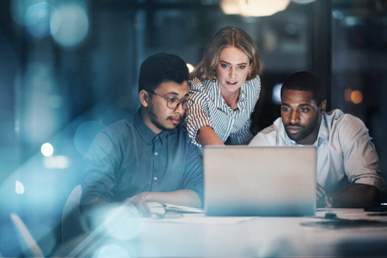Business people working together on a laptop in their office late at night
