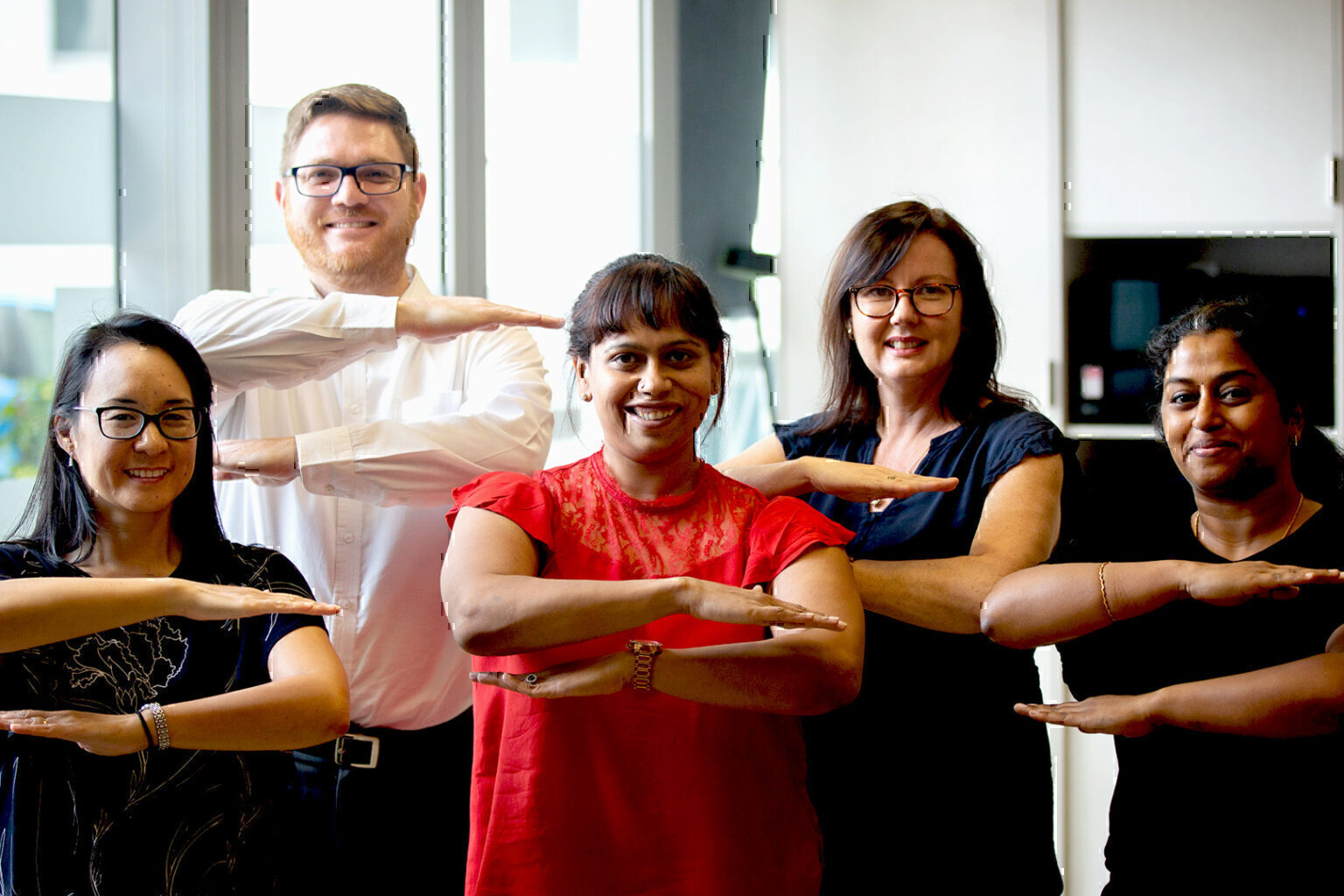 Group of smiling CSG employees making the equality arm gesture