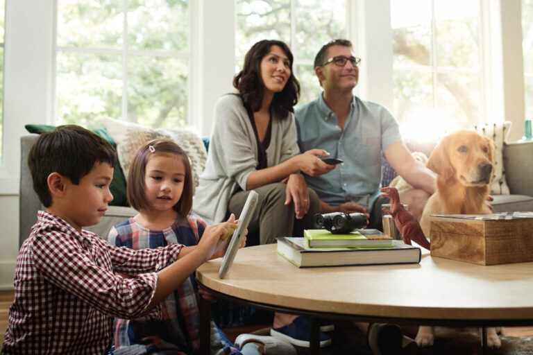 Family in living room with the children playing on a tablet