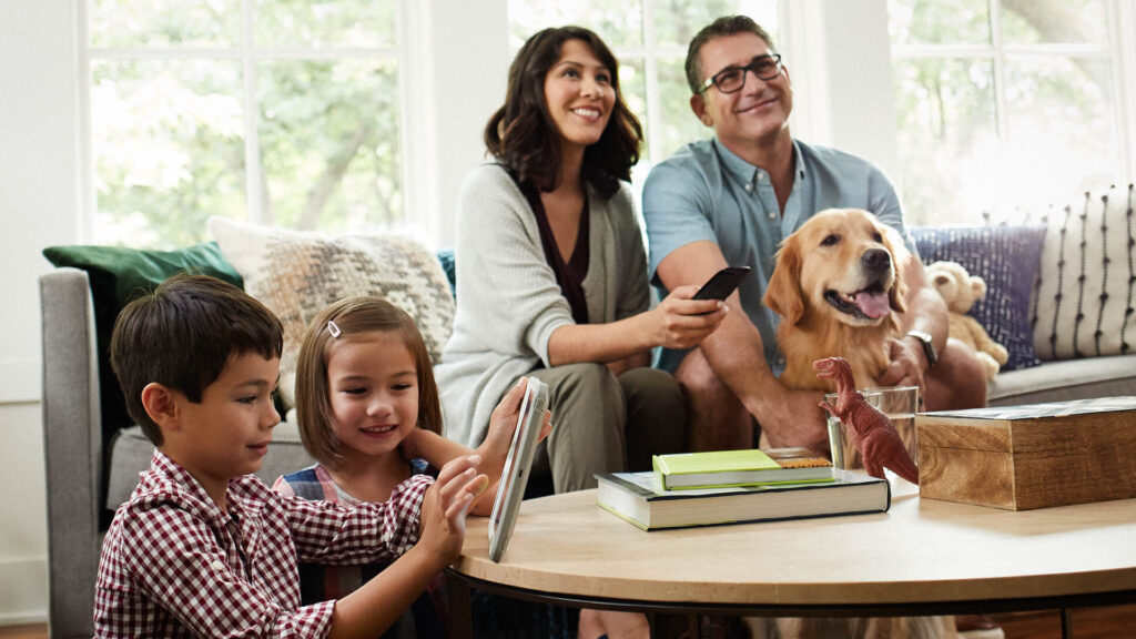 Family in living room with the children playing on a tablet