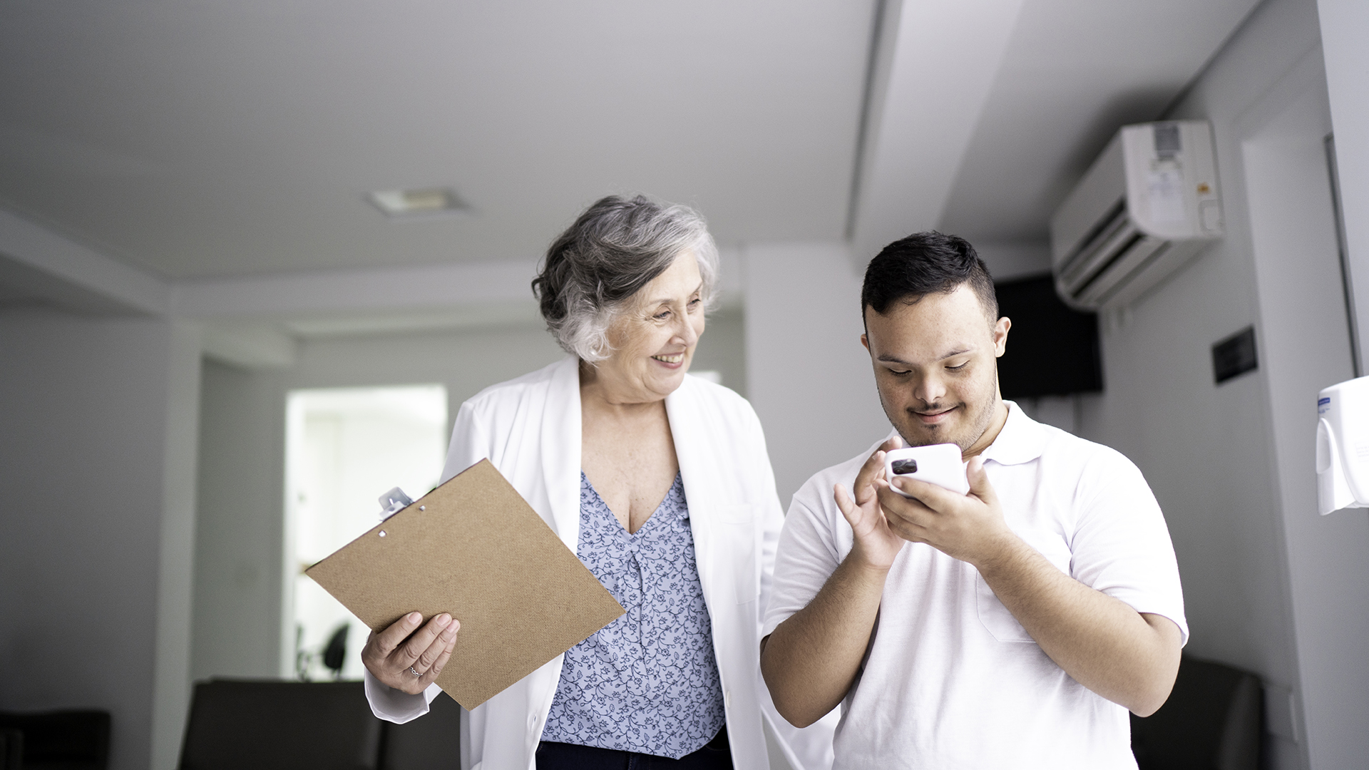 Female doctor with clipboard talking with man who is on his phone