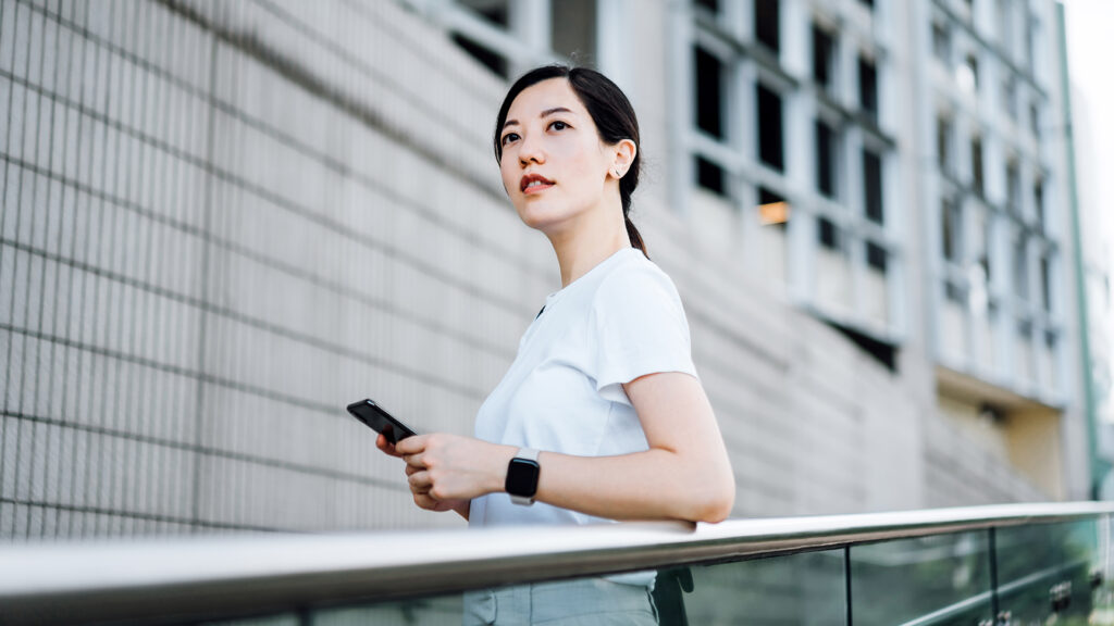 Businesswoman leaning on the rail outside an high-rise corporate building in the city