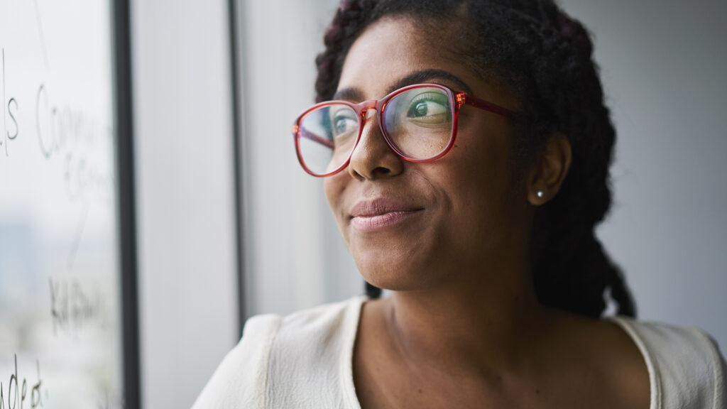 Cheerful businesswoman looking out window in conference room