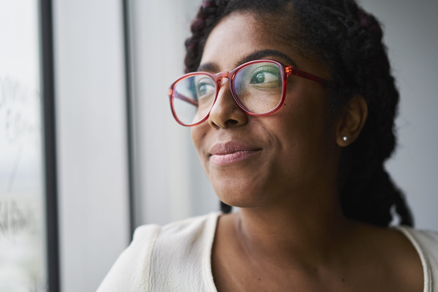 Cheerful businesswoman looking out window in conference room