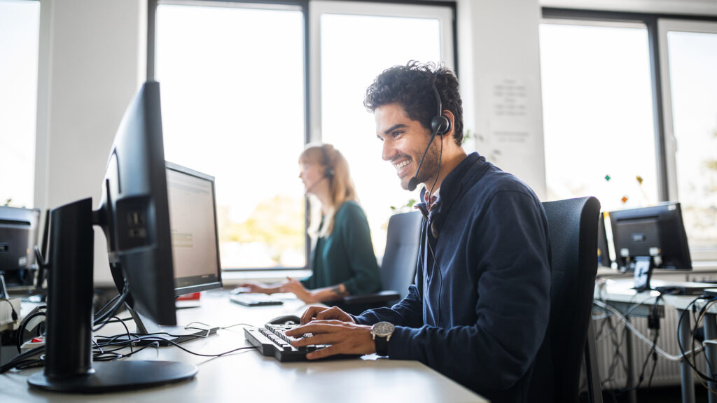 Smiling customer service representative using computer at desk