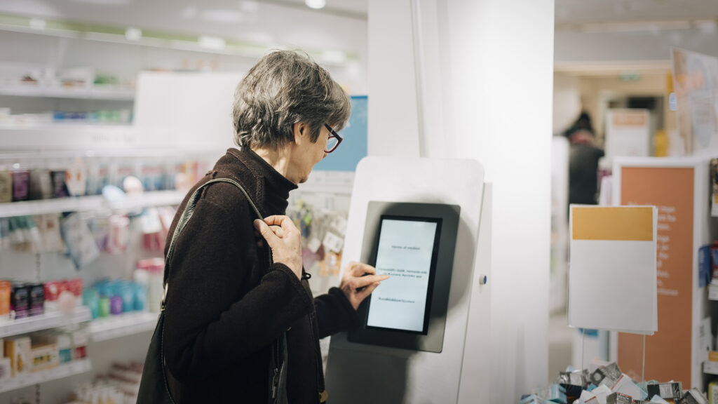 Woman using kiosk at pharmacy store