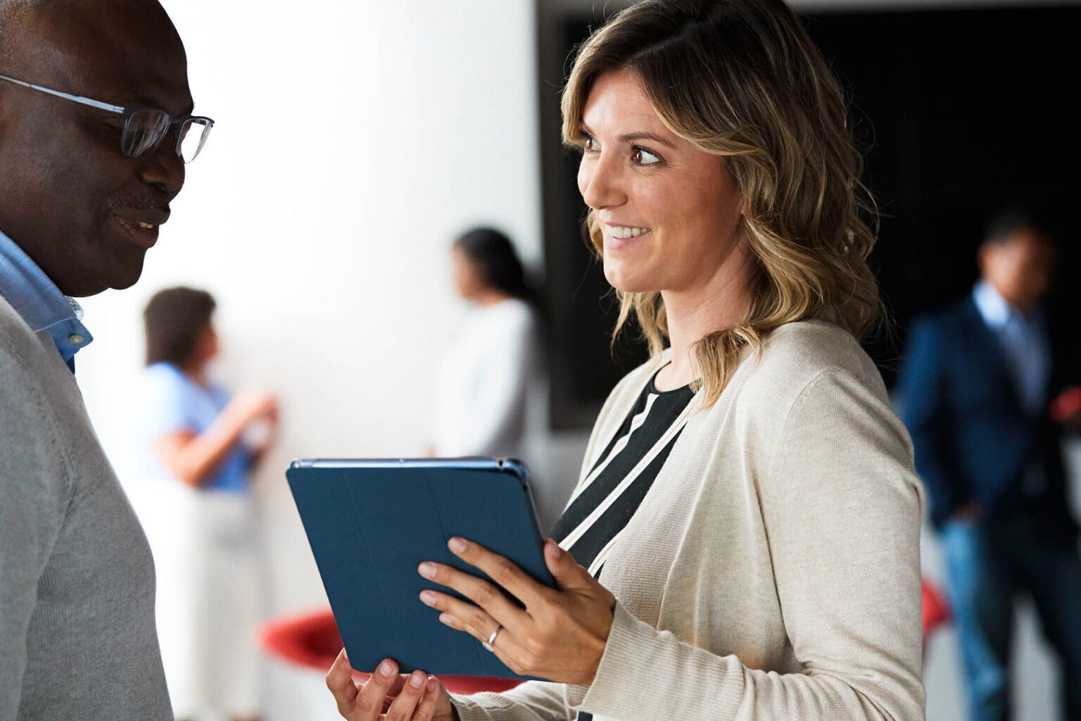 Man and woman discuss something from a tablet that the woman is holding