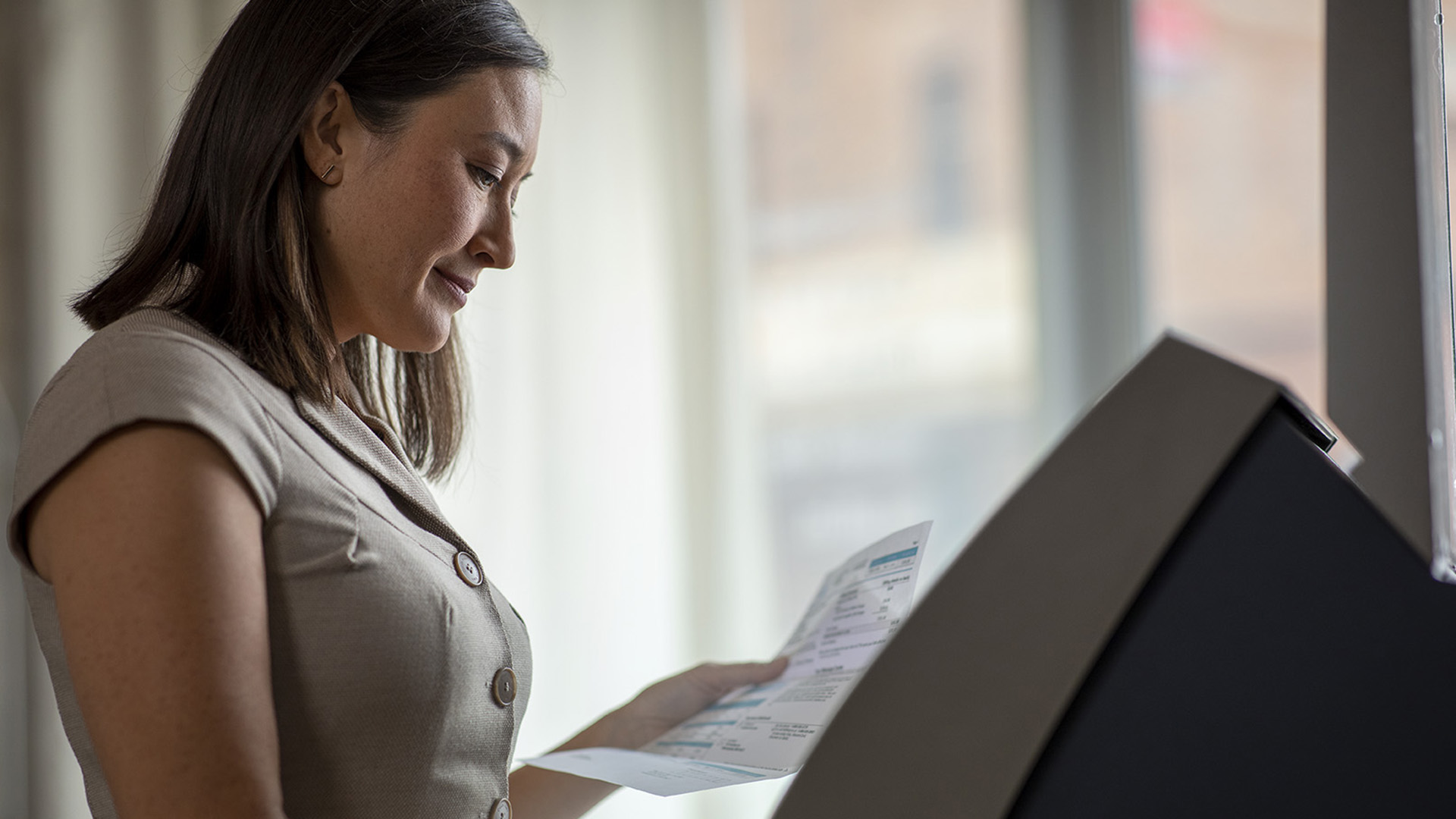Woman grinning while holding a billing statement