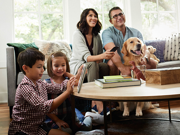 Family in living room with the children playing on a tablet
