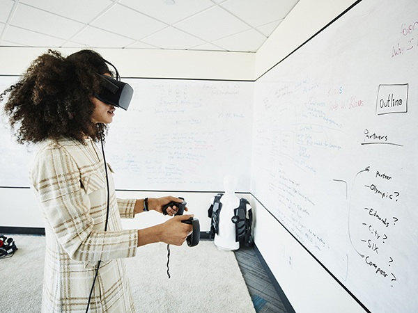 Female engineer testing program on virtual reality headset in computer lab