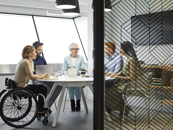 Male and female professionals in a modern-looking conference room engaged in lively discussion