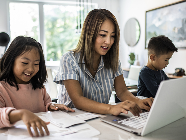 Mother working from home surrounded by children