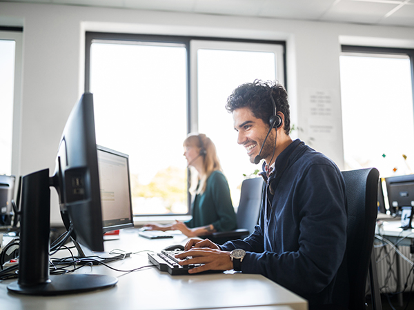 Smiling customer service representative using computer at desk