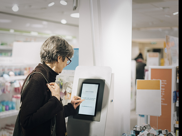 Woman using kiosk at pharmacy store