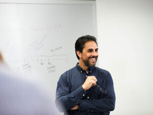 Male professional standing in front of a whiteboard smiling to his audience