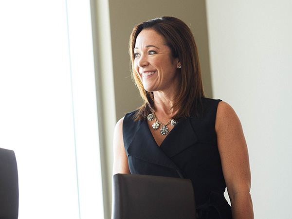 A professional woman in a conference room smiles looking out the window