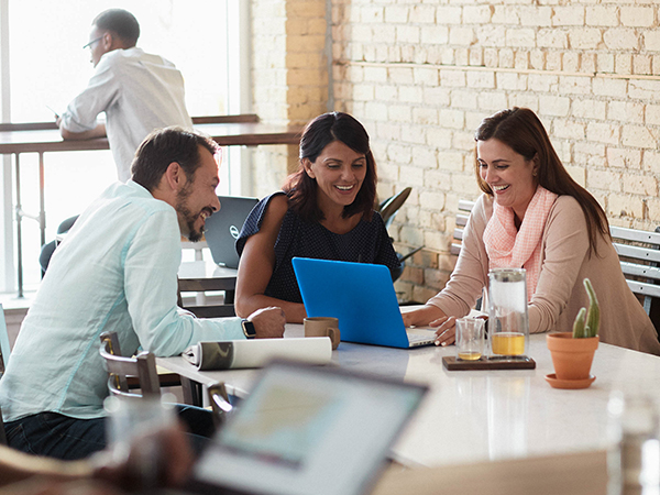 people sitting at a table in coffee shop looking at laptop