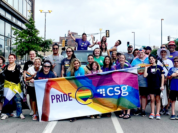 Crowd of CSG employees posing with the CSG LGBTQ+ Pride parade banner