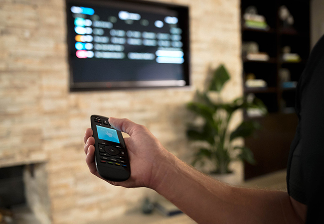 Cable technician holding a remote in front of a TV