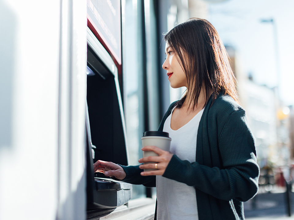 Young woman withdrawing cash money at the ATM