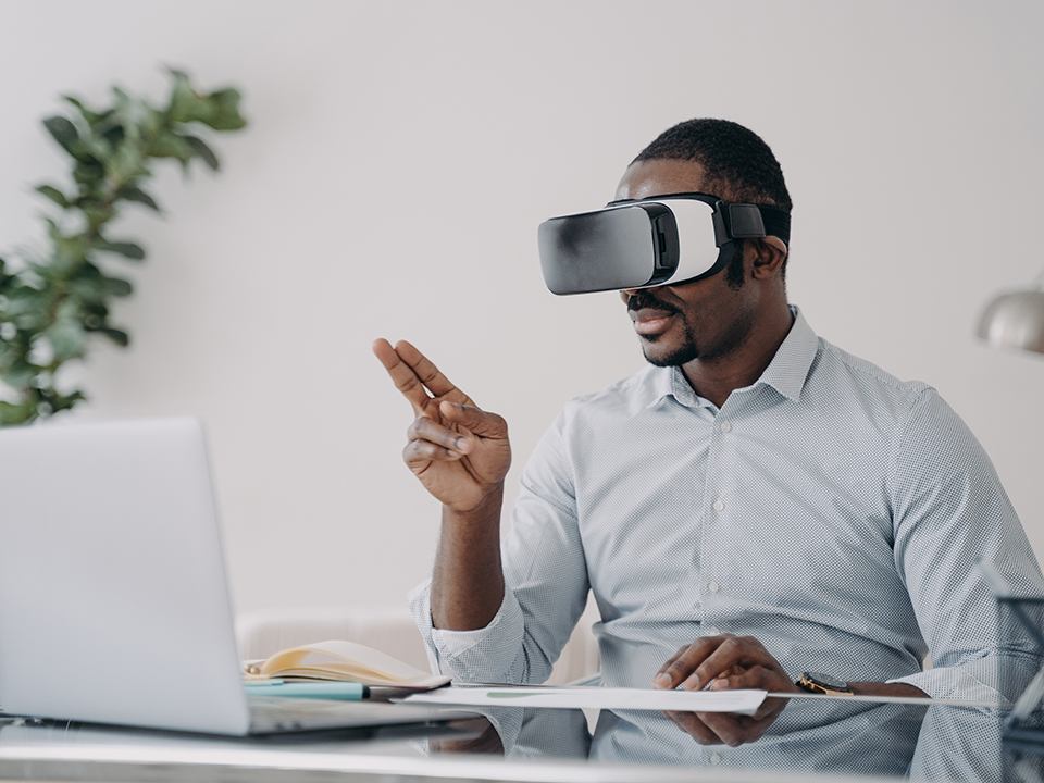 Businessman wearing virtual reality glasses works at his laptop