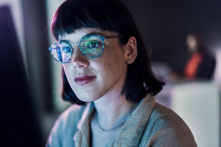Business woman face, computer and ux coding of young employee with blue light and glasses