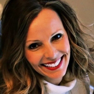 Cheerful woman with shoulder-length hair and a beige turtleneck.