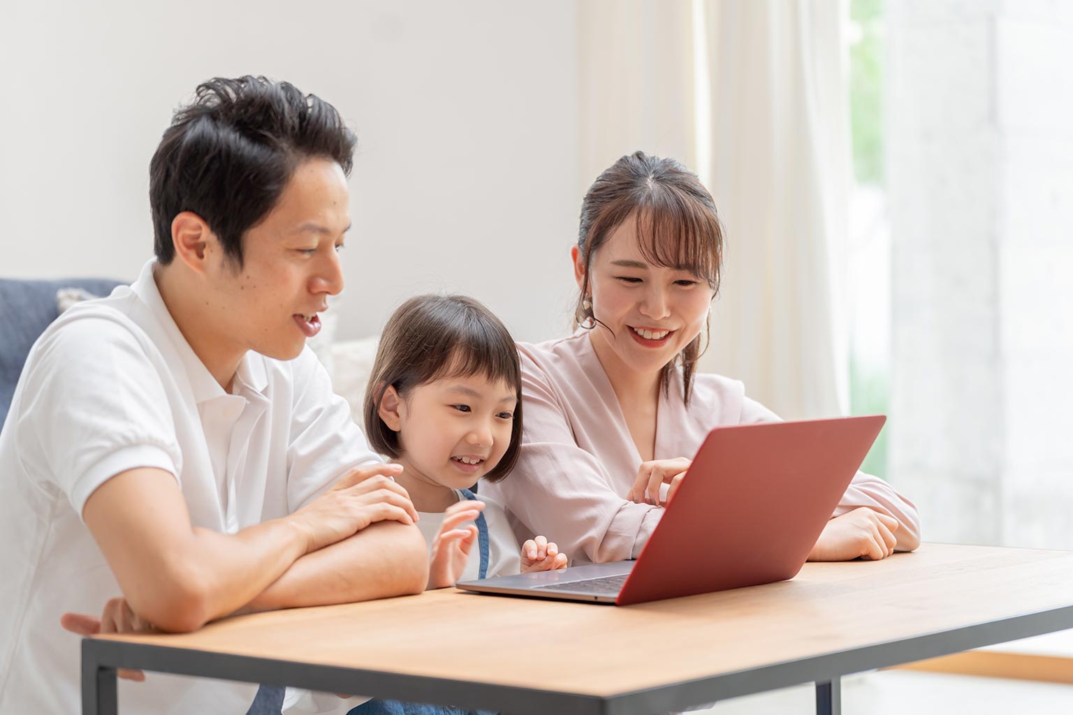 Happy Asian family gathered around a laptop computer