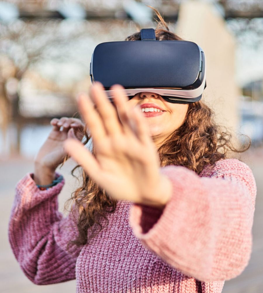 Smiling woman touches the screen in the virtual world of the metaverse. She wears VR goggles.