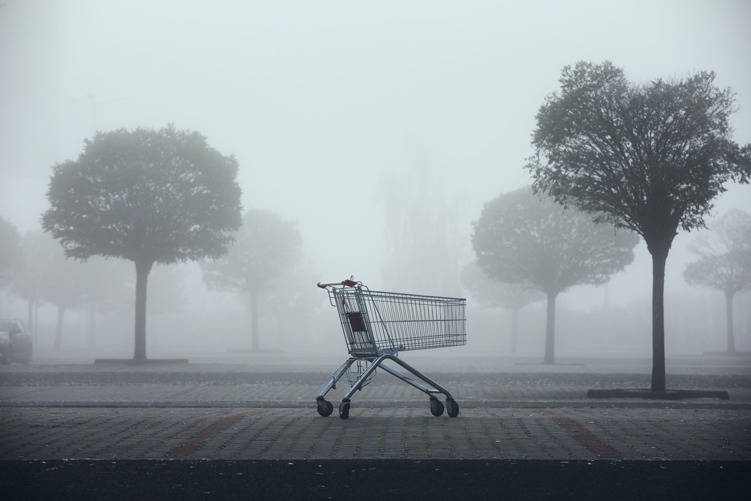 Abandoned shopping cart on parking lot in thick fog.