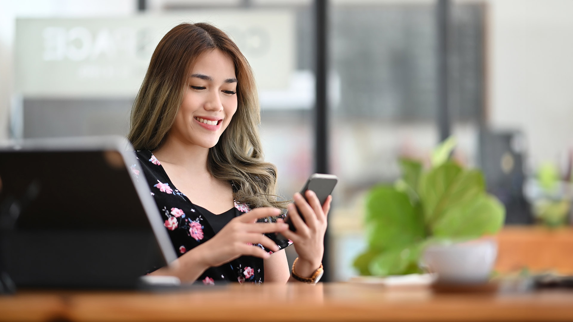 Beautiful Asian woman uses her phone at office desk