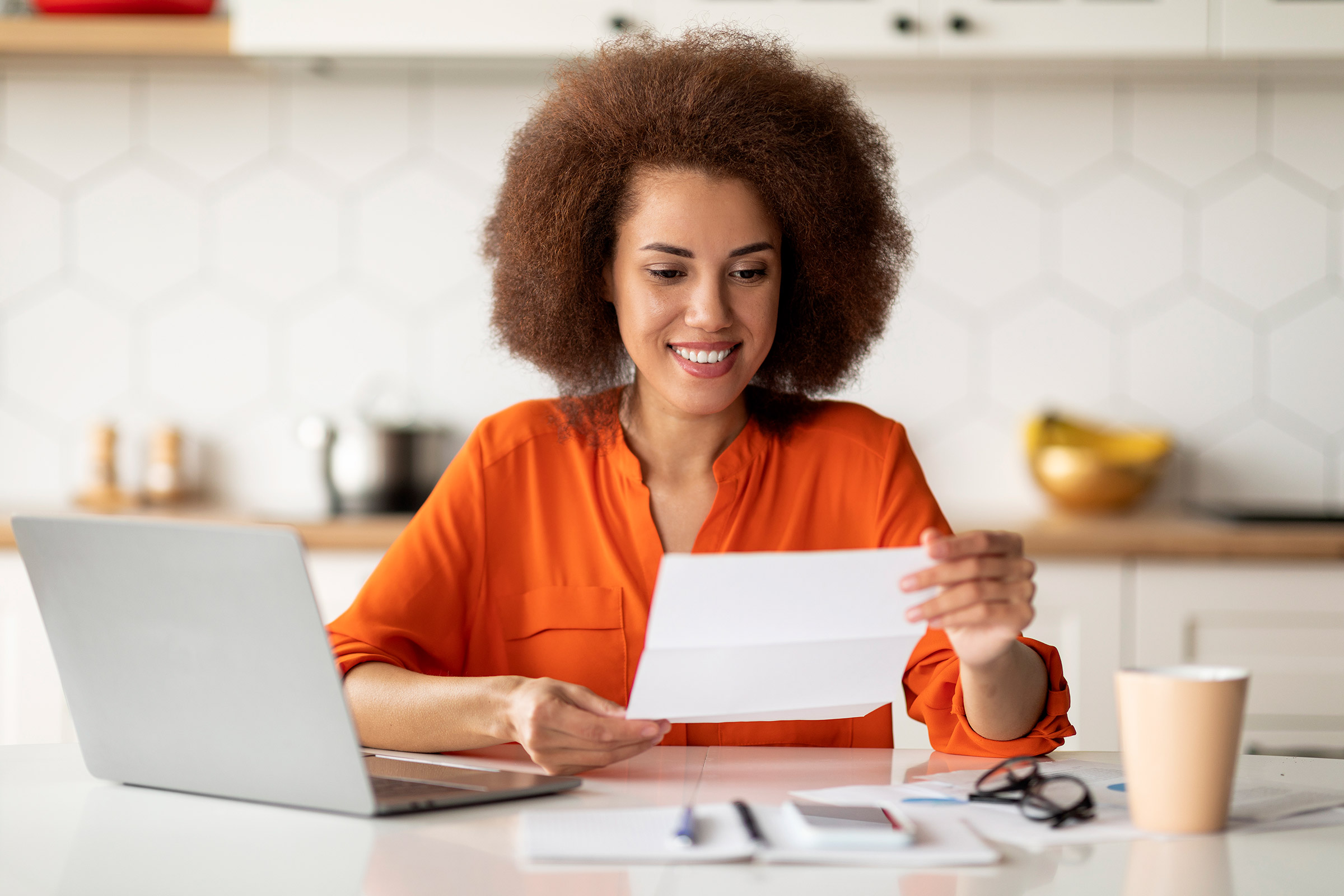 Woman looking at document with laptop next to her