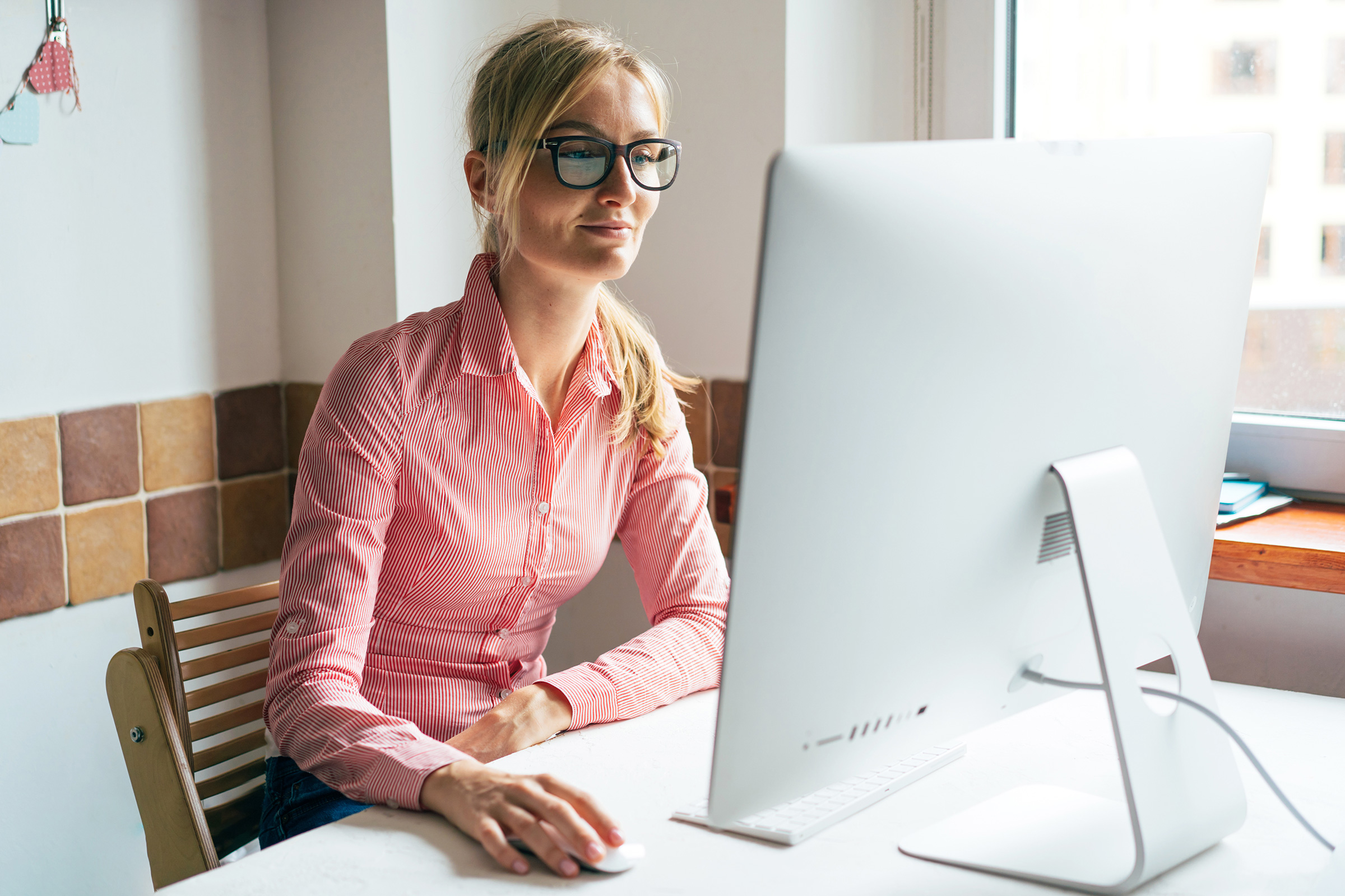 Business woman with glasses looks at computer monitor