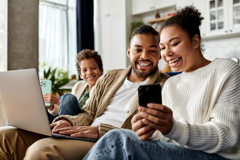 captivated family on couch with laptop phone