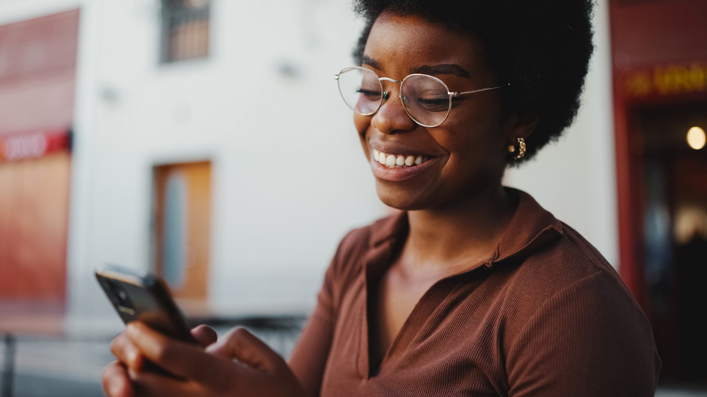 cheerful dark skinned woman sincerely smiling while texting