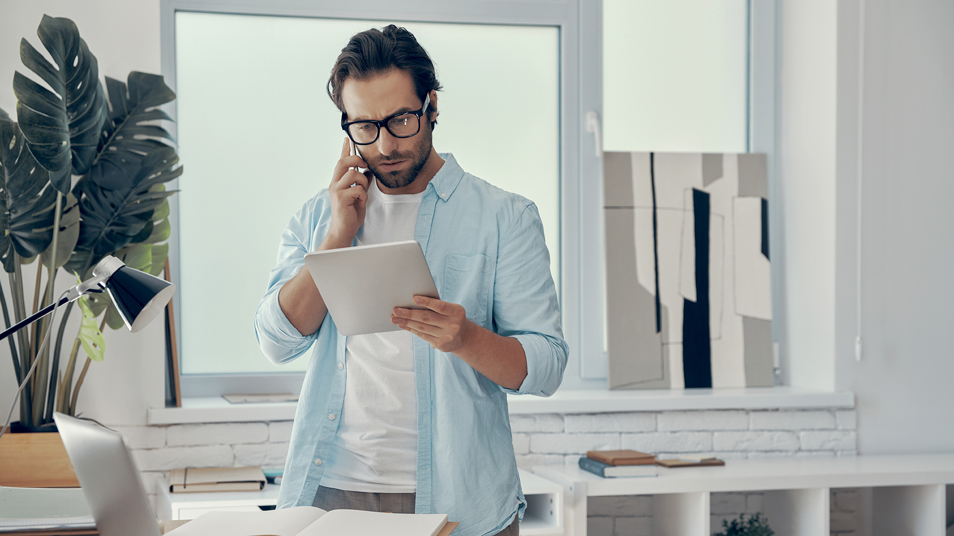 Confident business man using phone and tablet