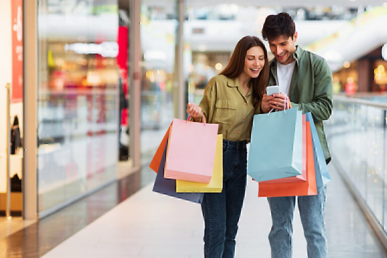 Happy couple shopping and checking phone