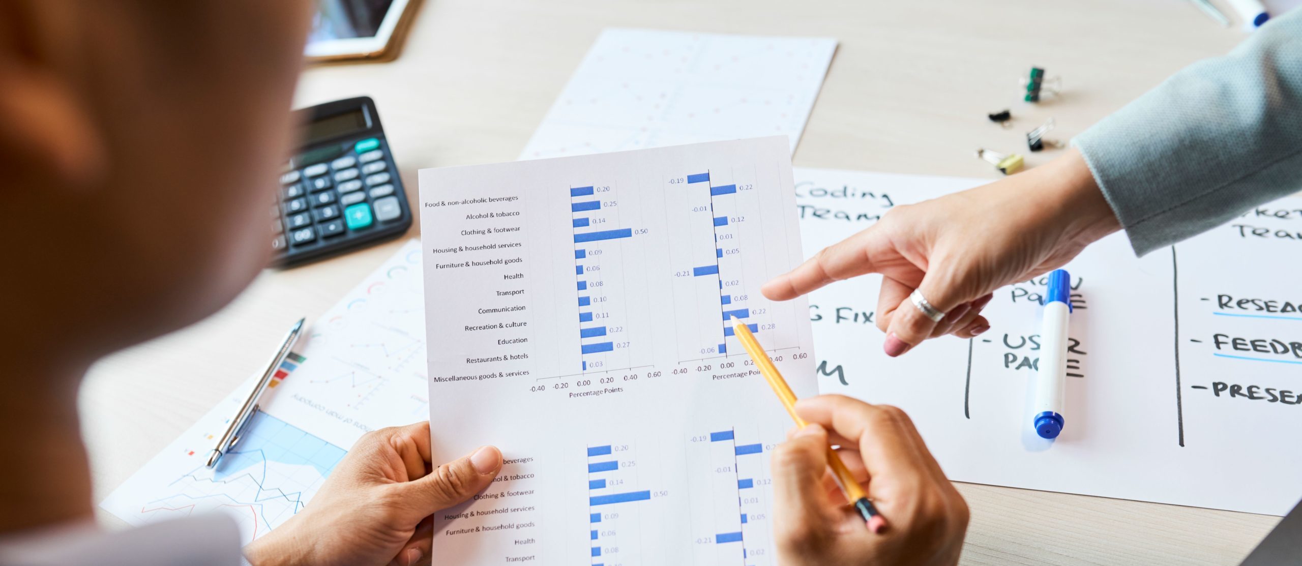 Person examining a financial bar chart with a colleague pointing at it.