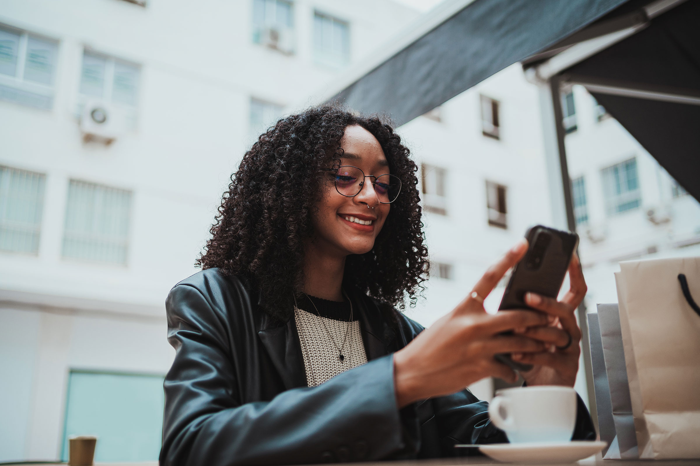 Woman at coffee shop smiling while looking at her phone