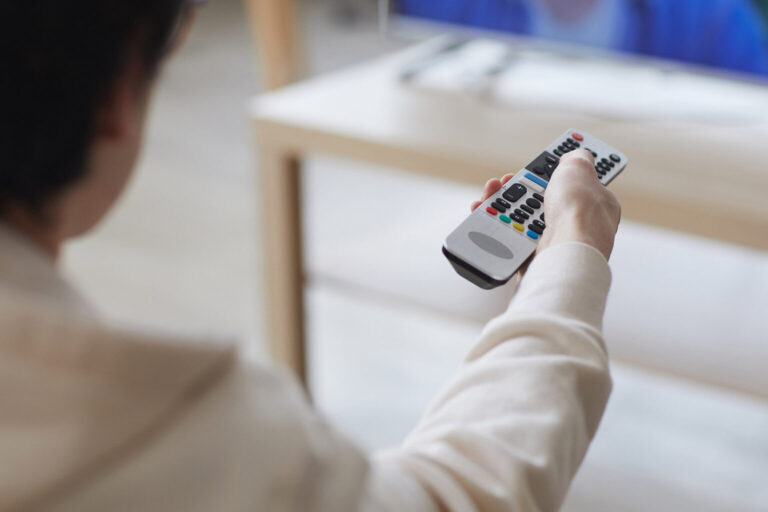 Hand holding remote pointed at television