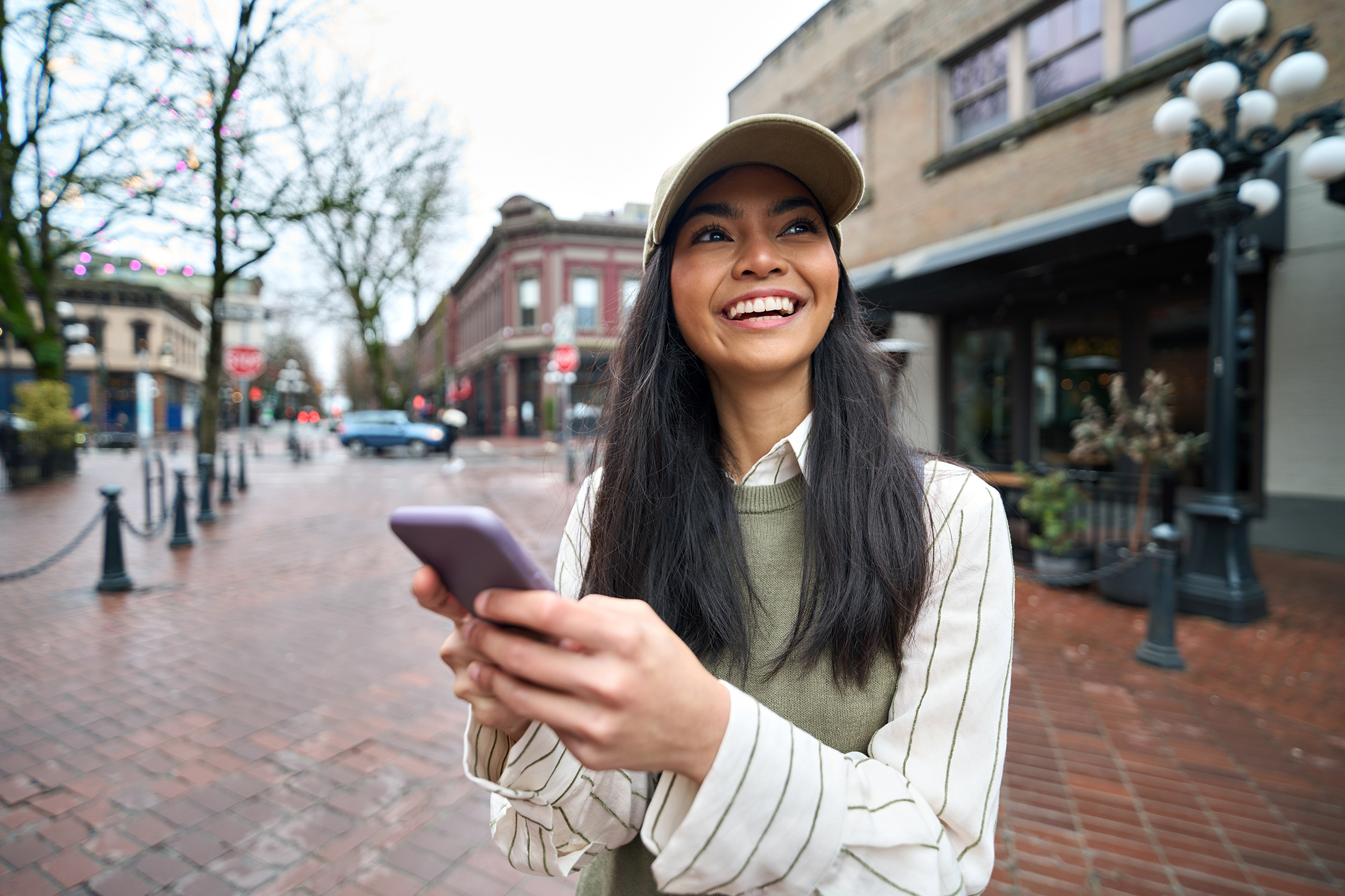 Happy Asian teen girl using smartphone standing on city street with smartphone.