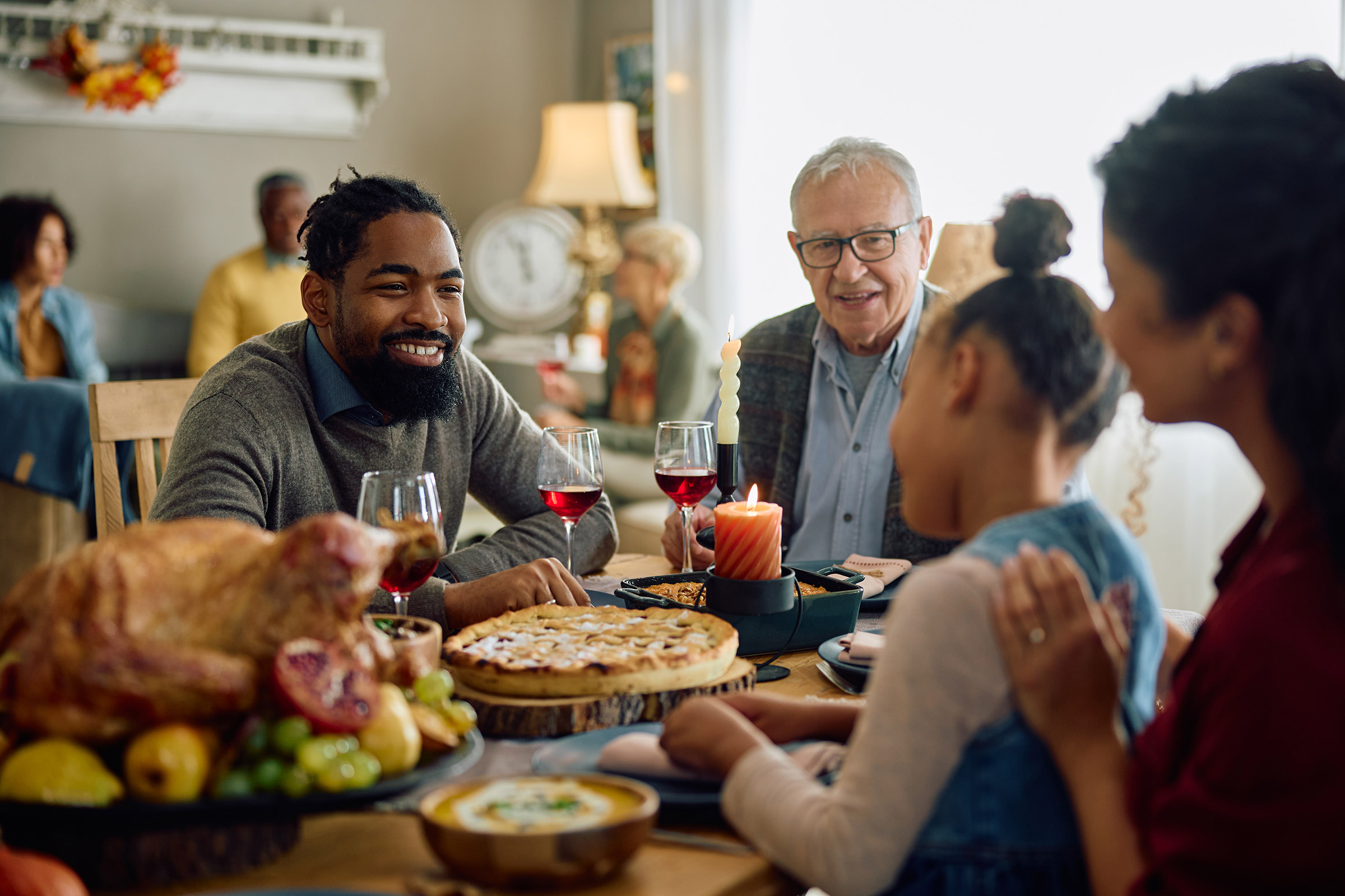 Happy black man talks with family during Thanksgiving meal