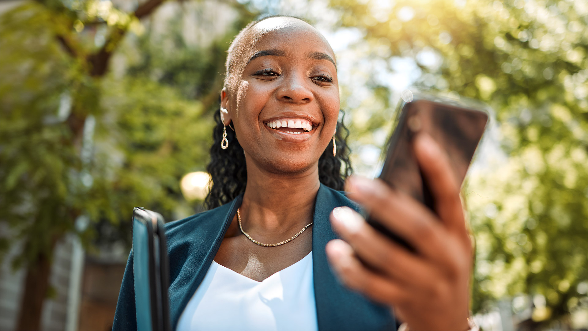 Happy black woman using her phone on city street