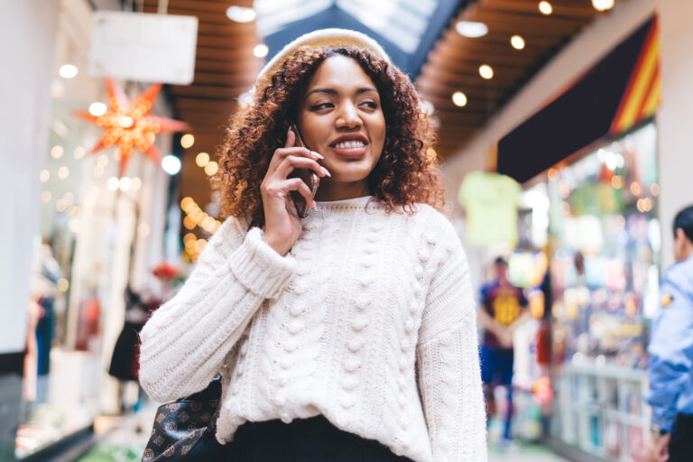 happy black woman talking on smartphone in shopping mall