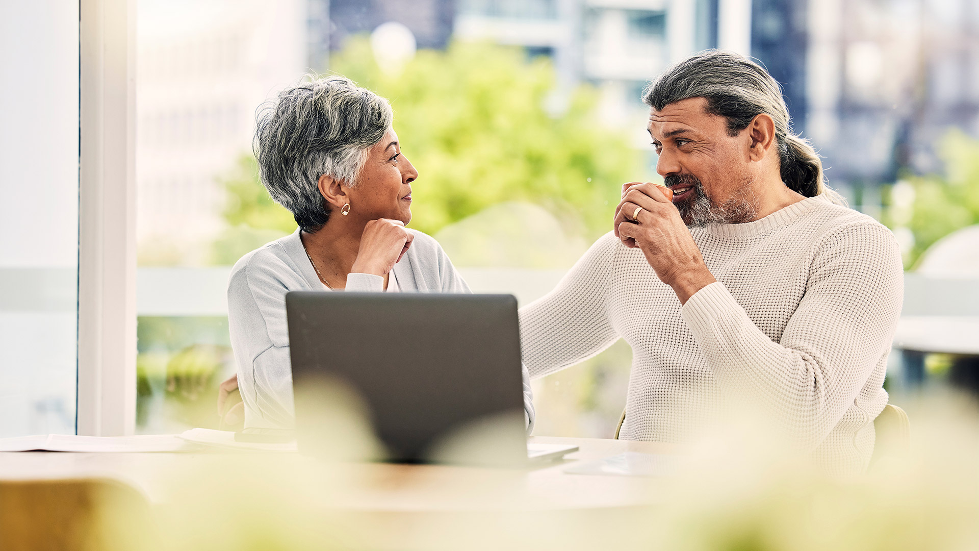 Senior couple chatting at home with laptop and coffee