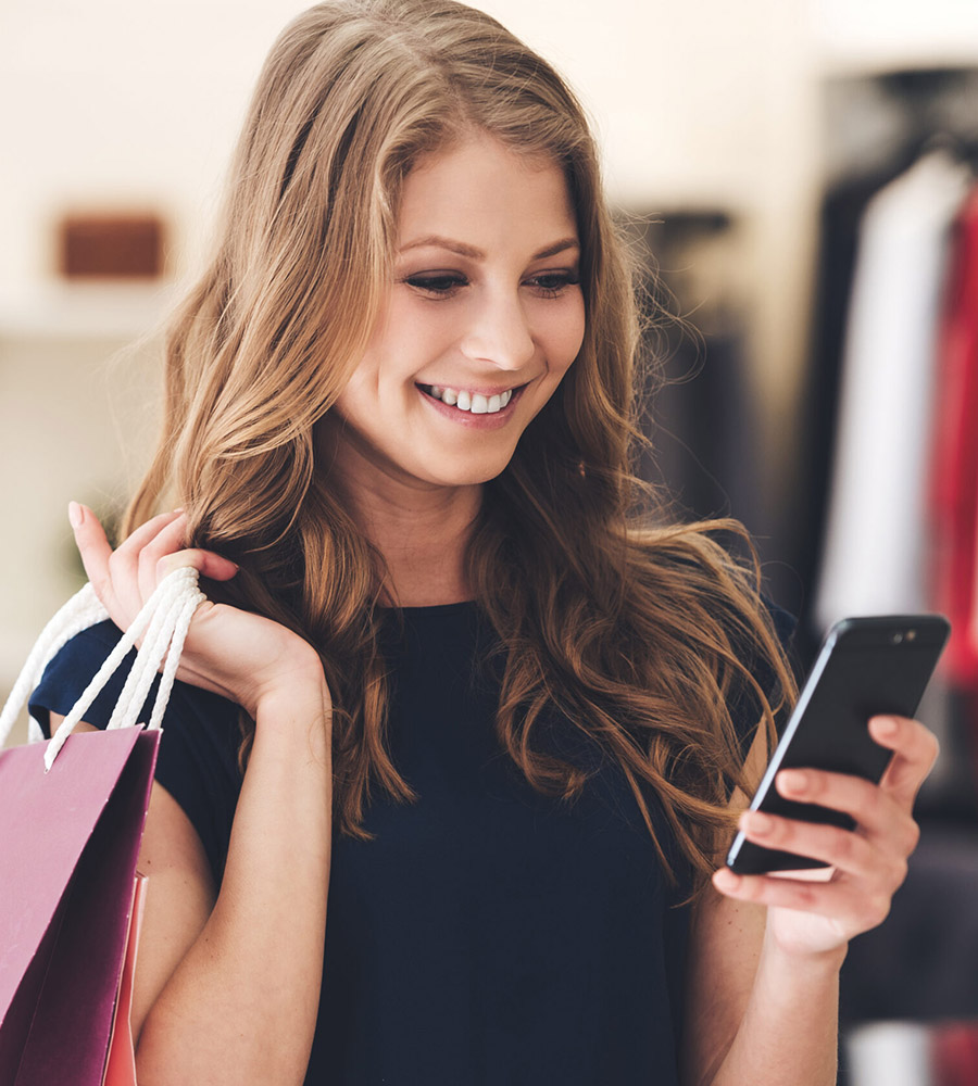 A young woman checks her phone while shopping.