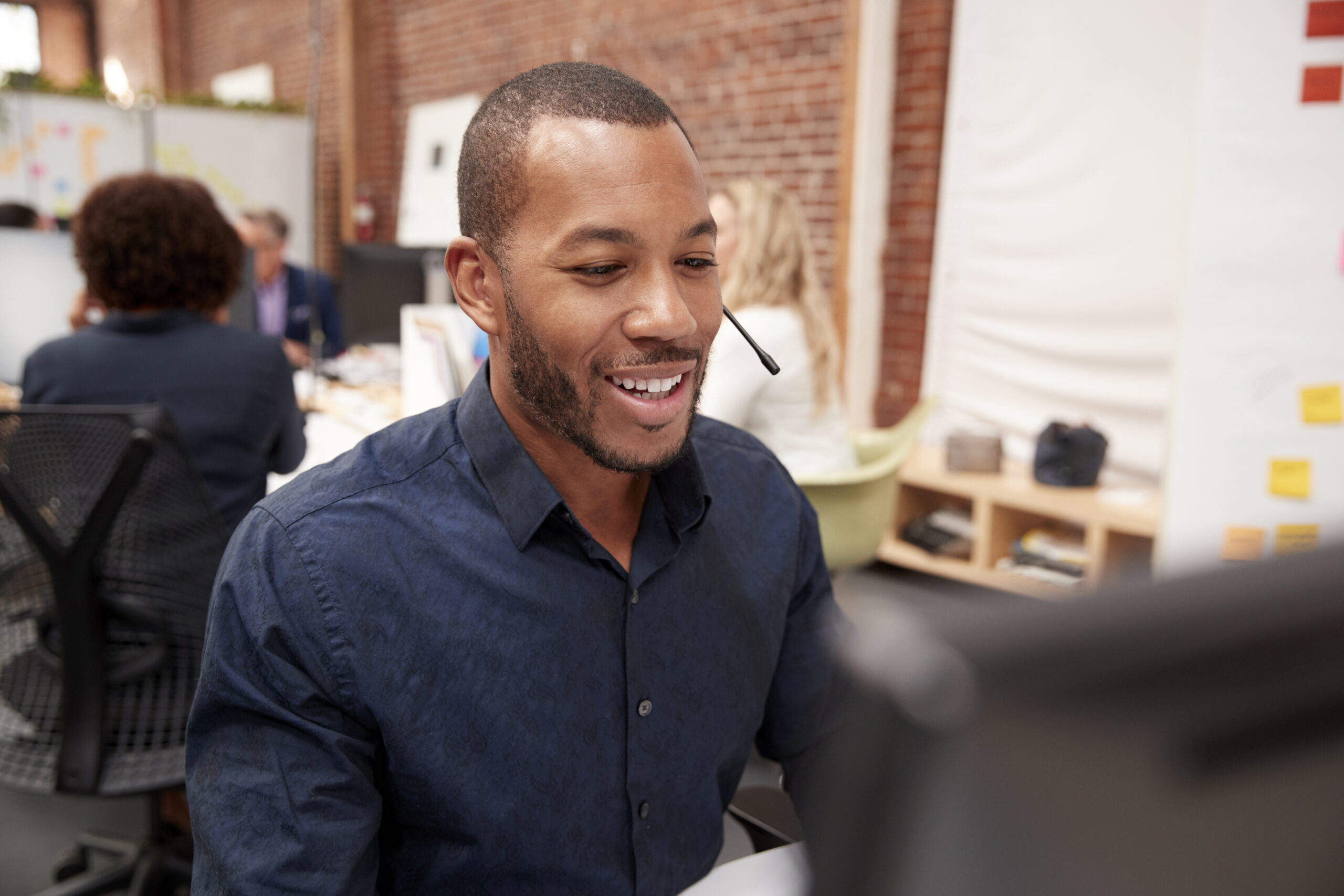 Male Customer Services Agent Working At Desk In Call Center