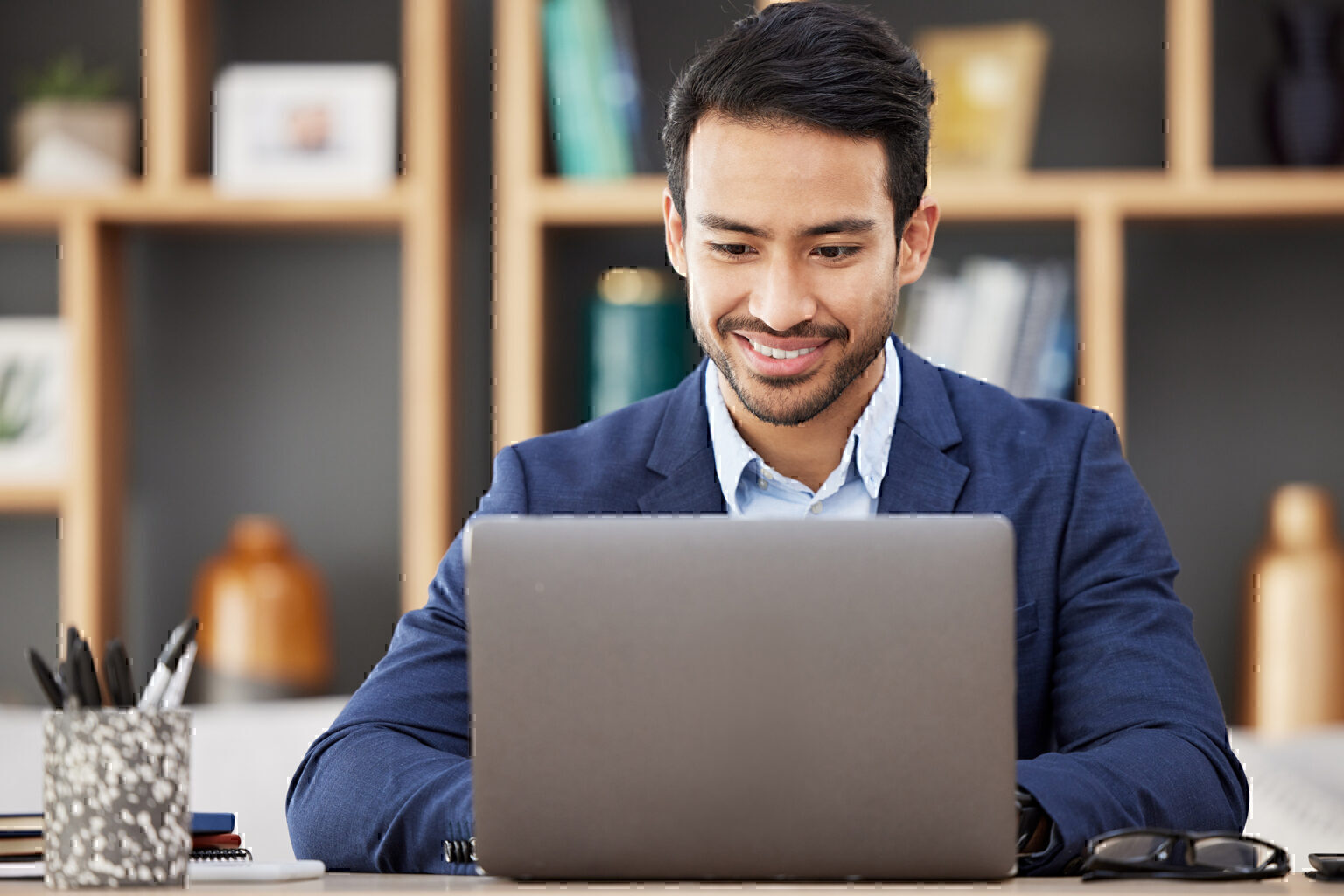 Man in office with laptop, smile and typing email, proposal or writing online report networking