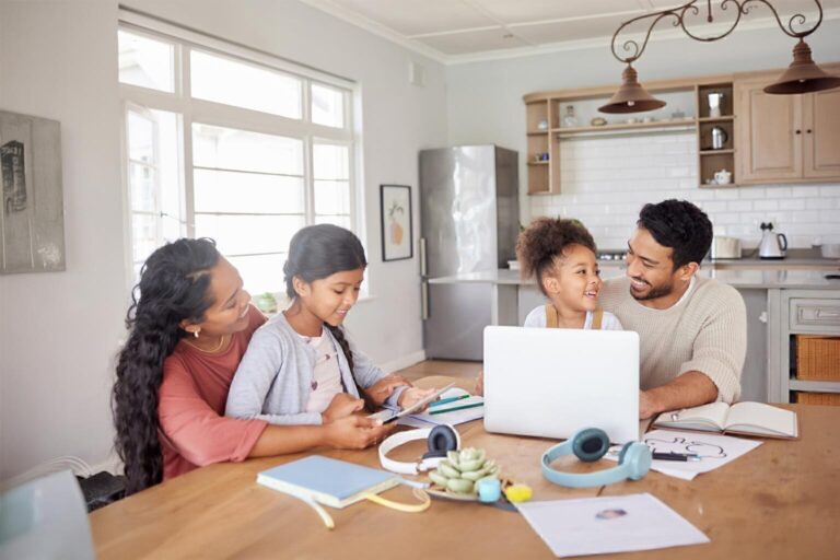 Family doing homework together at the kitchen tablet, laptop and tablet
