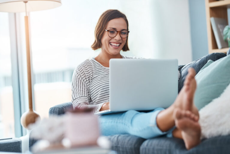 woman sitting on couch on laptop smiling